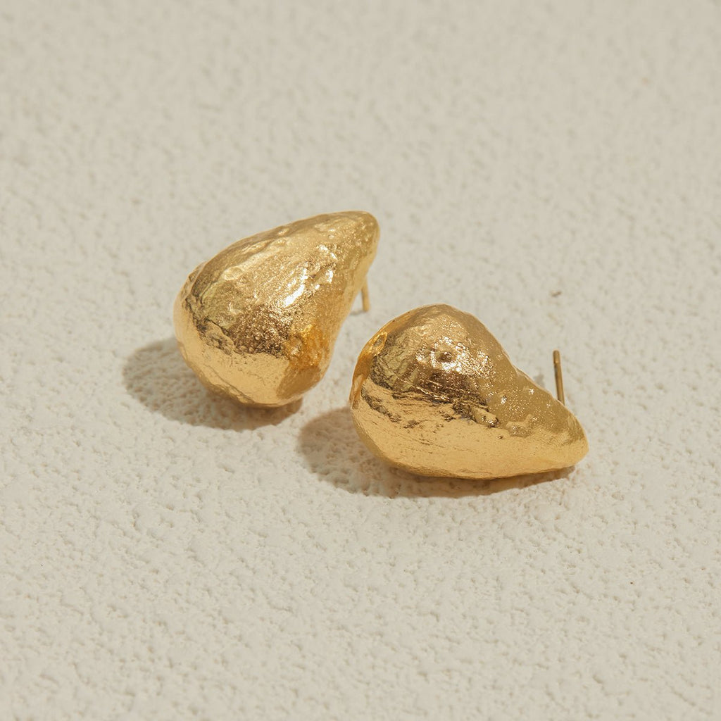 Pair of gold earrings on a light beige background