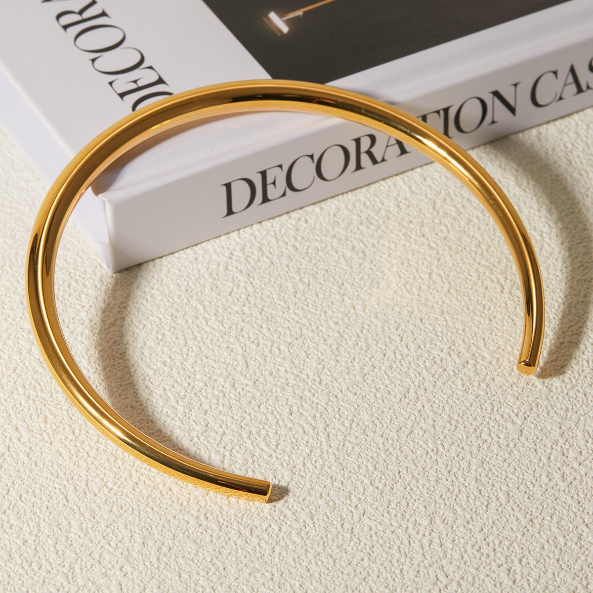 Gold bangle on a textured surface with a magazine in the background