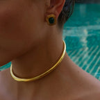 Close-up of a person wearing gold jewelry with a pool in the background