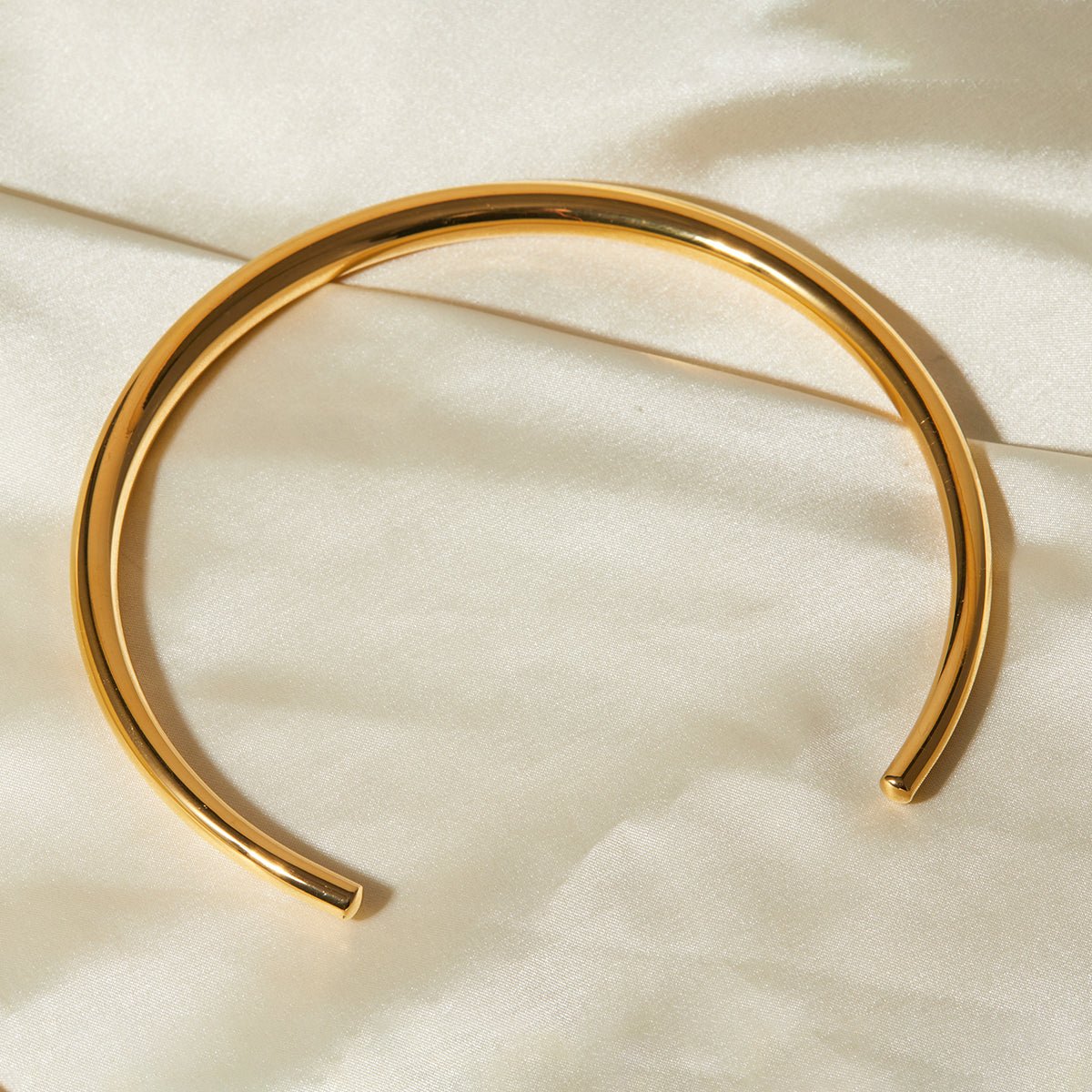 Gold bangle on a beige fabric background