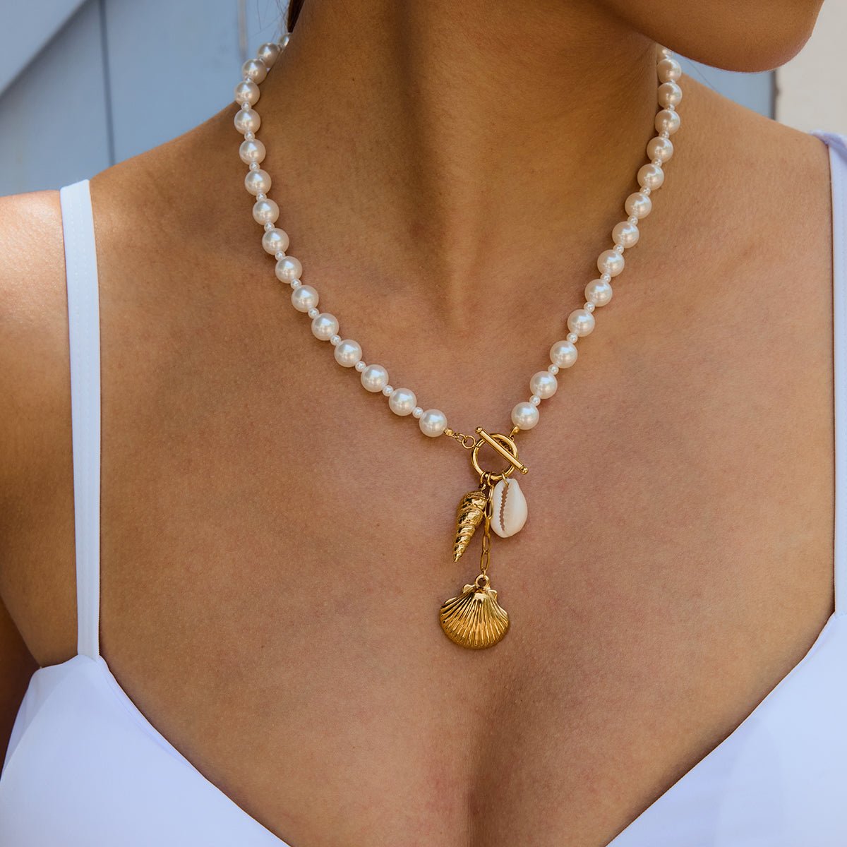 Pearl necklace with gold charms worn by a person
