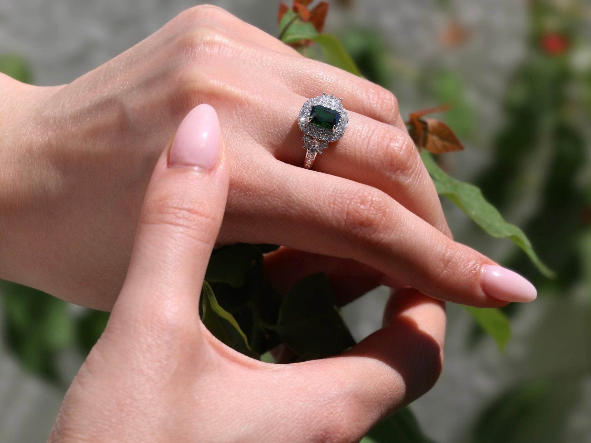 Elegant women’s ring featuring green gemstone and halo zirconia accents