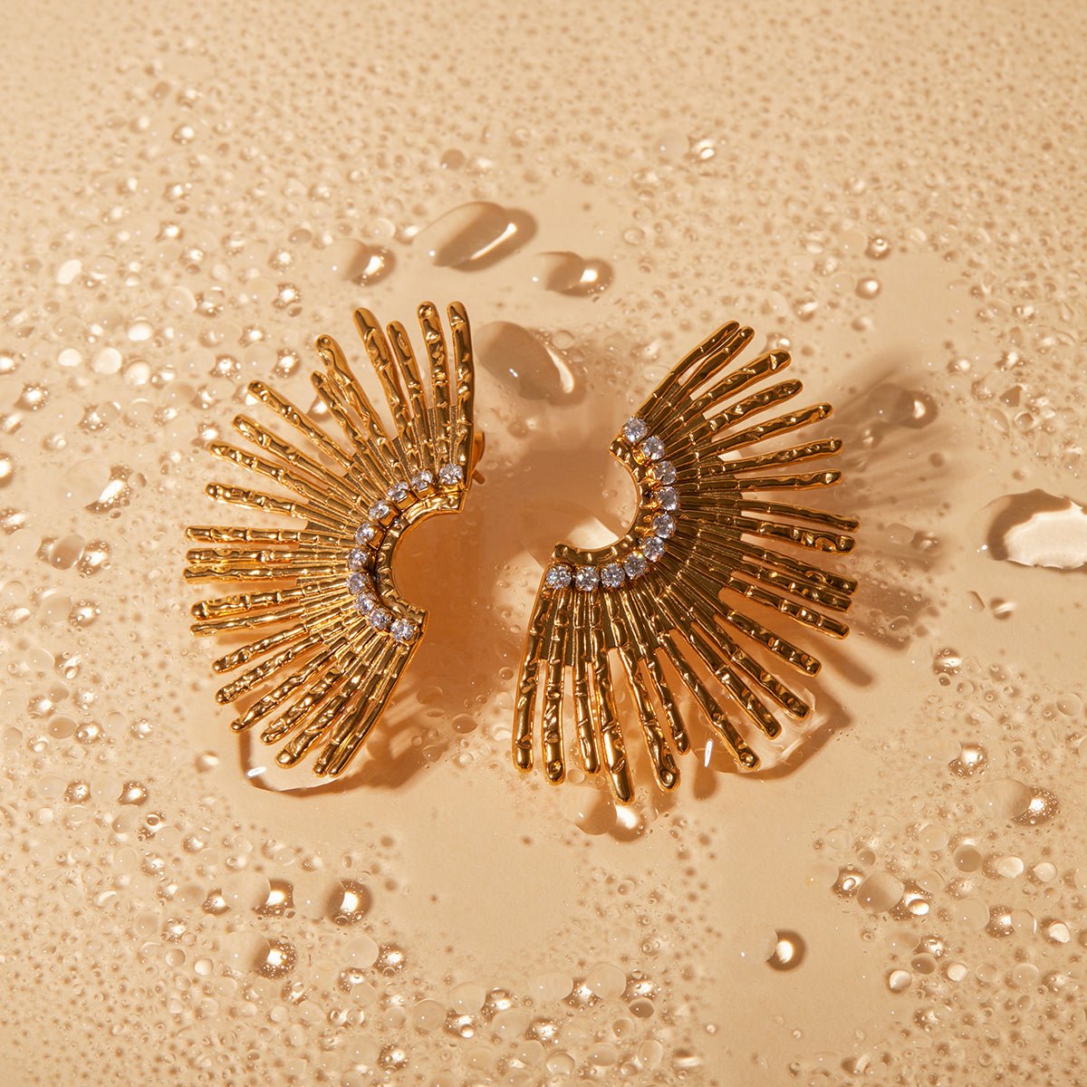 Gold earrings with fan-like design on a textured gold background