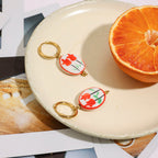 Two keychains with floral designs on a plate with an orange