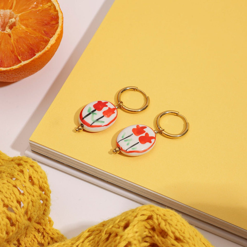 Keychain with floral design on a yellow surface with an orange and fabric in the background