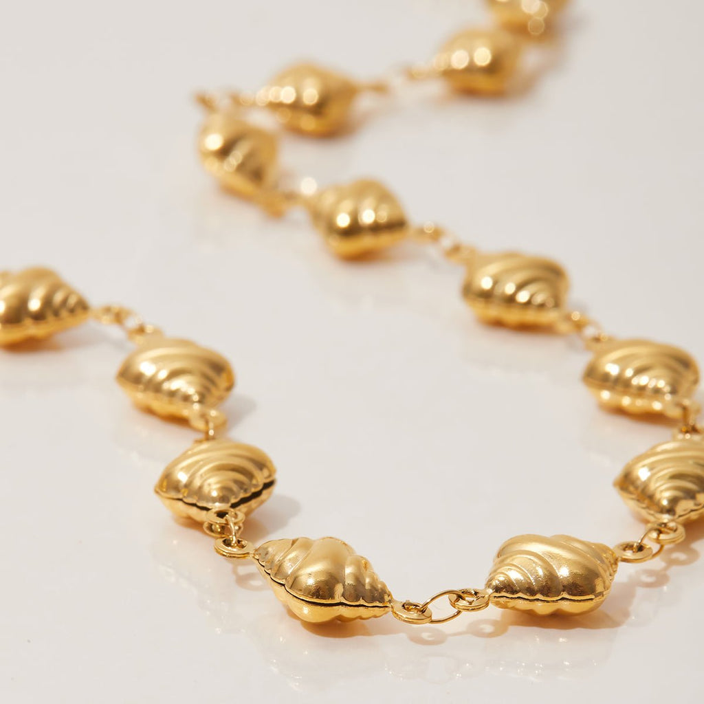 Gold necklace with shell-like links on a light background