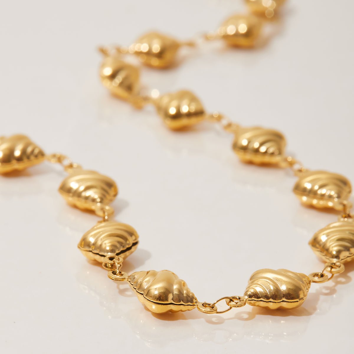 Gold necklace with shell-like links on a light background