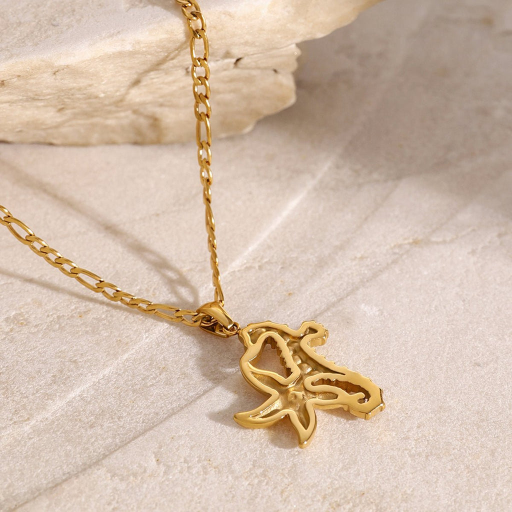 Gold necklace with a starfish pendant on a light stone background