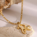 Gold necklace with a dragonfly pendant on a textured beige surface