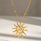Gold sun-shaped pendant necklace on a neutral background