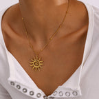 Gold sun-shaped necklace on a person wearing a white top with silver embellishments.