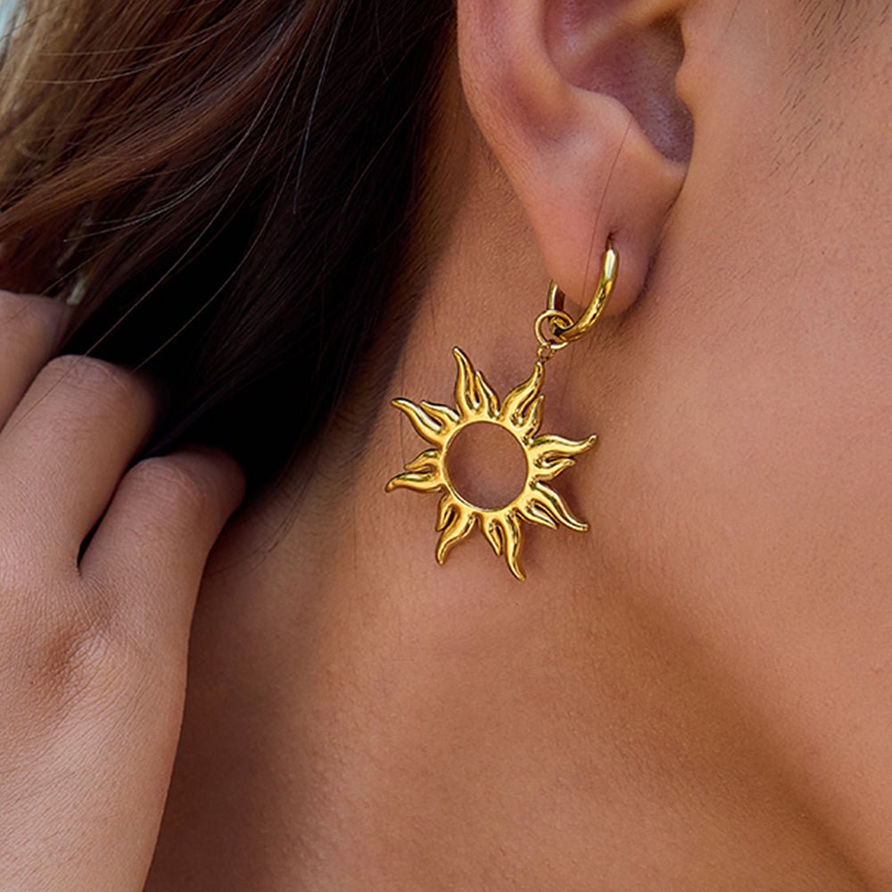Gold sun-shaped earring worn by a person