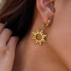 Gold sun-shaped earring worn by a person