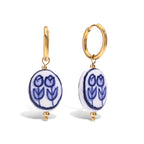 Gold hoop earrings with blue tulip designs on white background