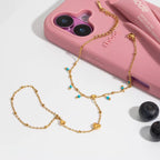Gold chain necklace with heart-shaped pendants on a pink phone case with 'th mee' branding.