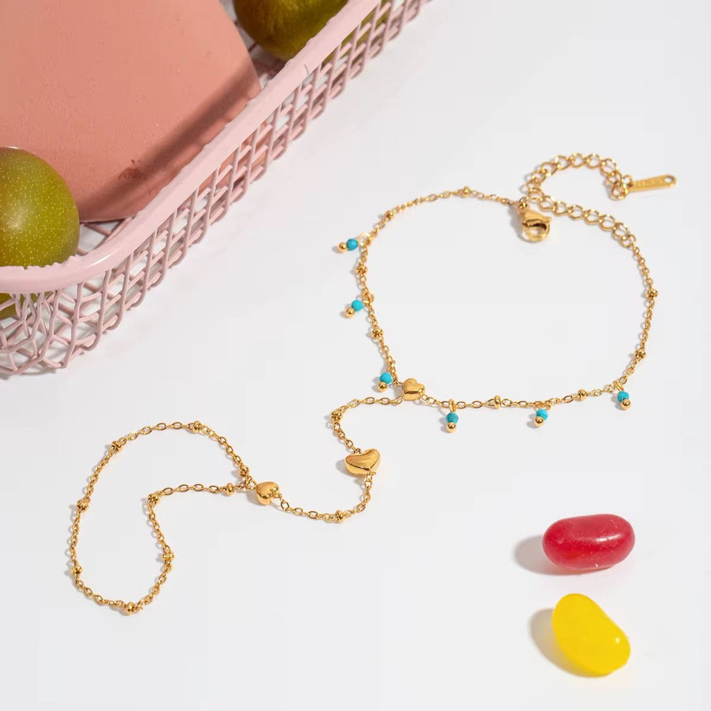 Gold necklaces with colorful beads on a white surface