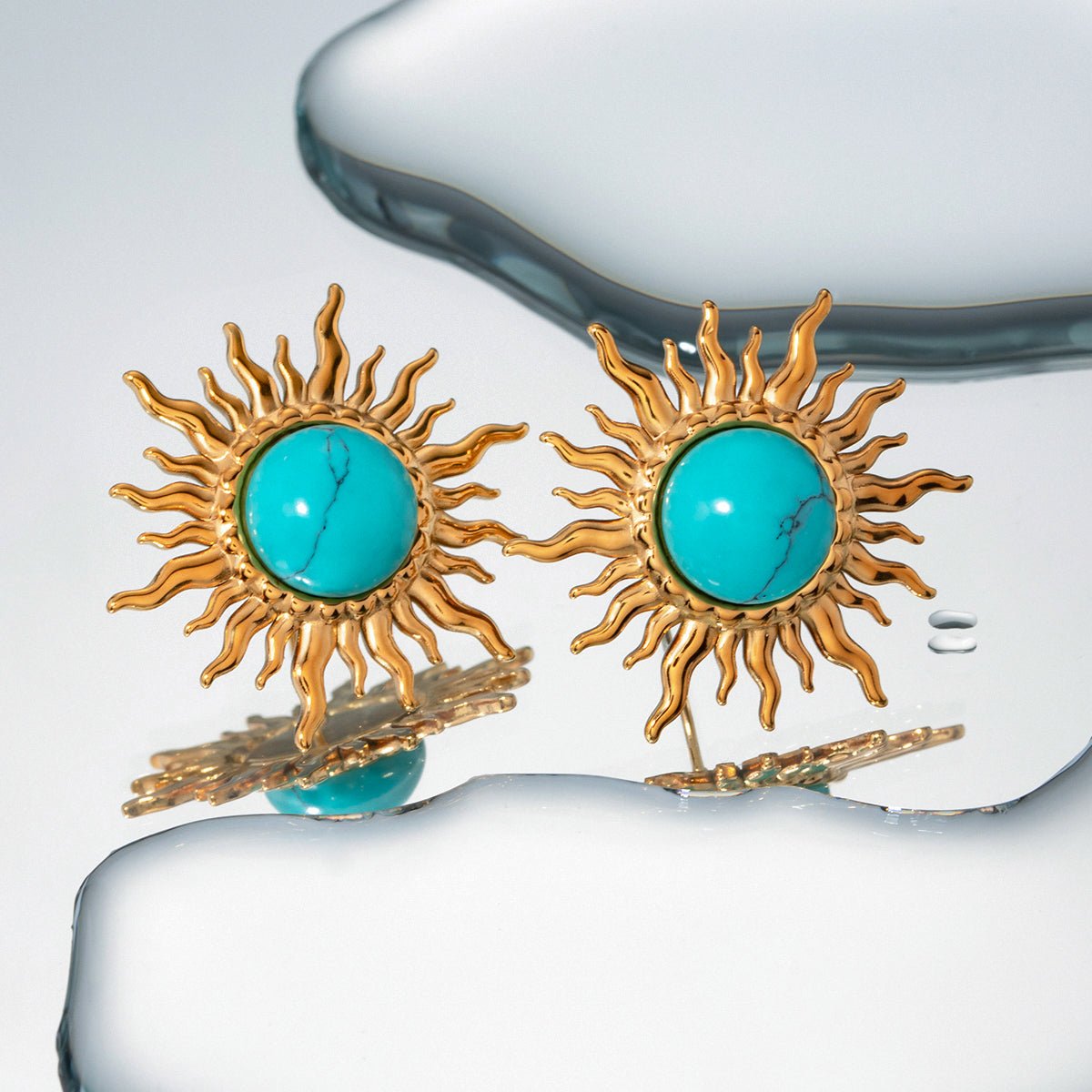 Sun-shaped earrings with turquoise stones on a white background