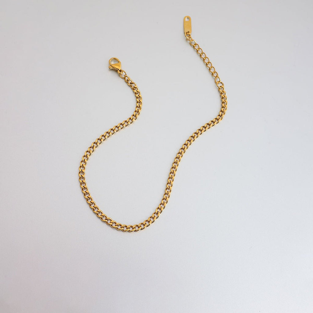 Gold chain bracelet on a light gray background