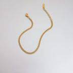 Gold chain bracelet on a light gray background