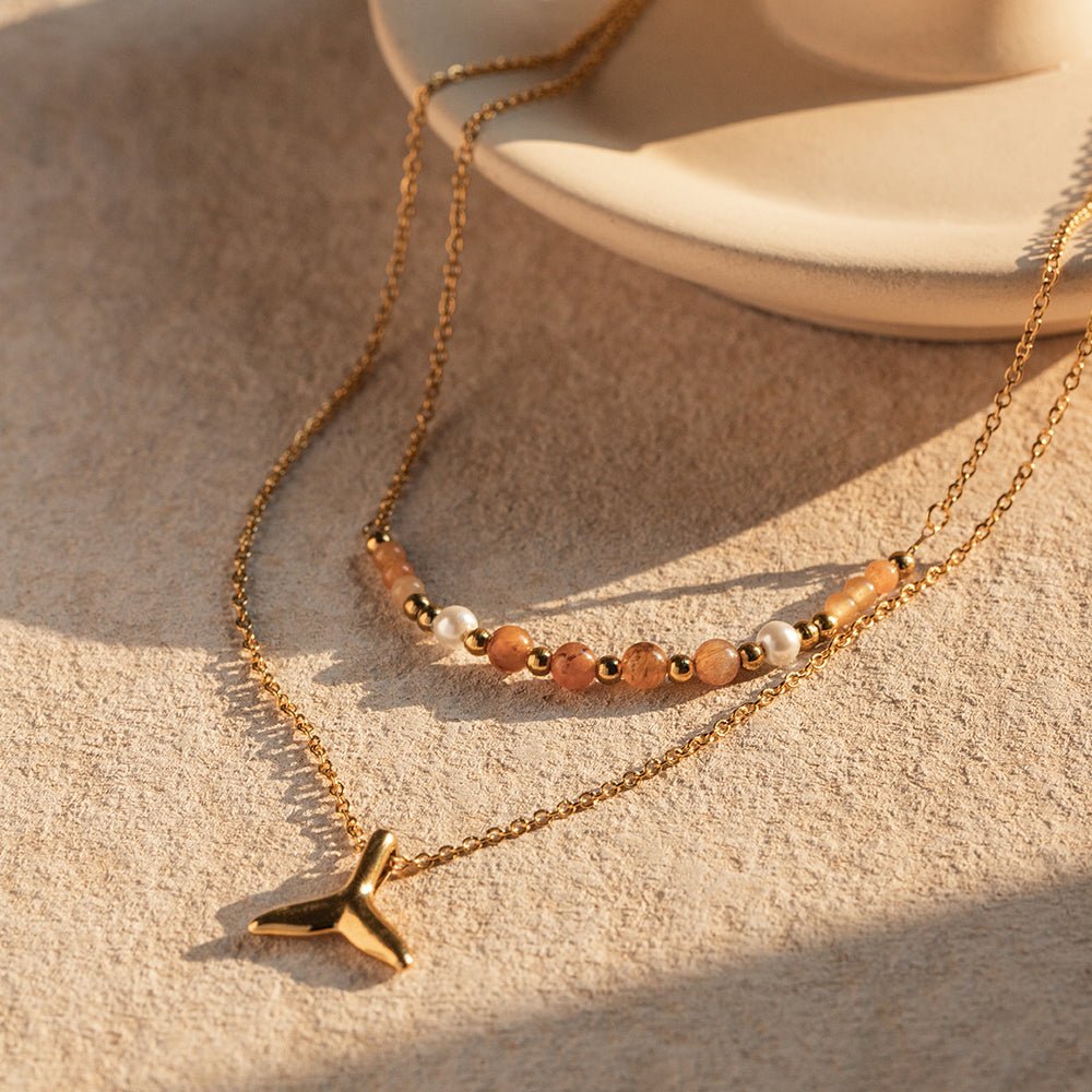 Gold necklace with star pendant on a textured beige surface