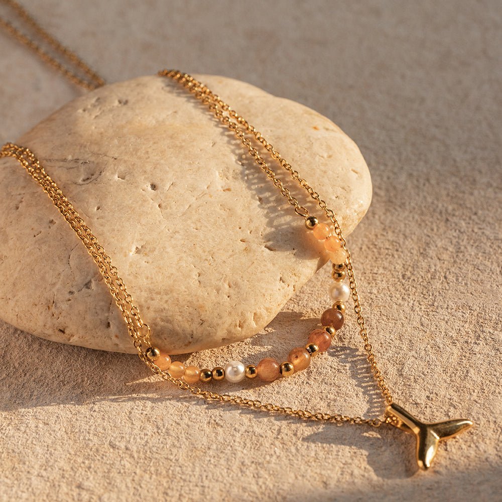 Gold necklace with beads on a stone surface