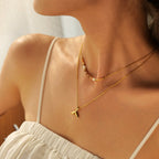 Close-up of a person wearing a gold necklace with a fish tail pendant.