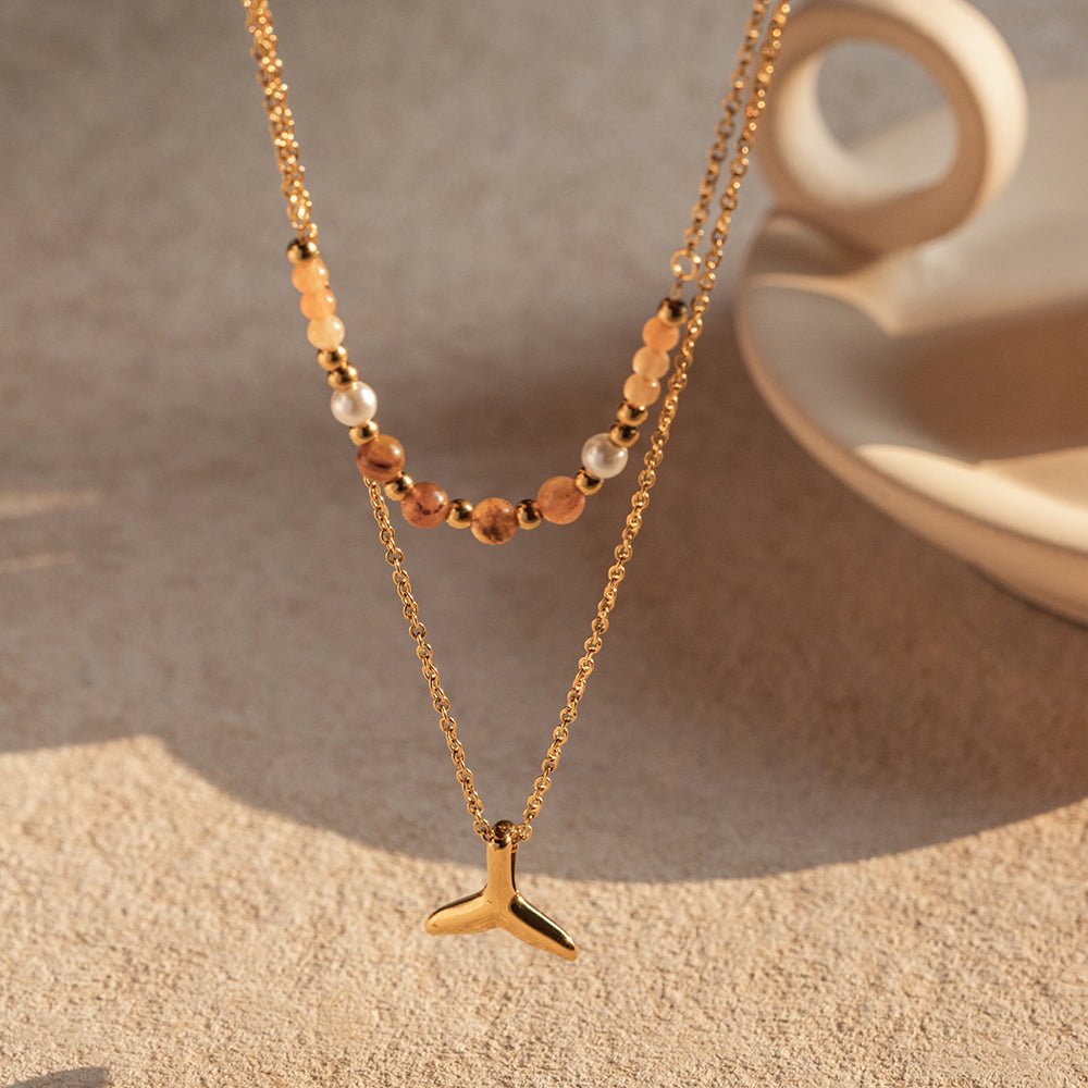 Gold necklace with a pendant on a textured surface